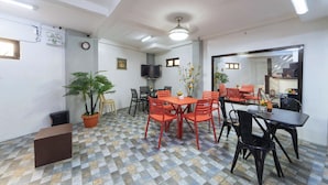 A dining area with a checkered floor, a ceiling fan, and a television mounted on the wall. - Reddoorz @ San Antonio Binan Laguna (Biñan City)