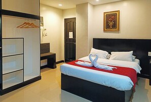 A hotel room with a bed, a wardrobe, a desk, and a wall-mounted picture. - Check Inn Hotel Dumaguete City By Reddoorz (Dumaguete)