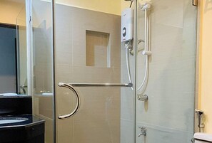 A modern bathroom with a glass shower enclosure, a handrail, a toilet, and a sink. - Check Inn Hotel Dumaguete City By Reddoorz (Dumaguete)