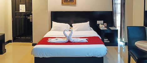 A hotel room with a bed, a nightstand, a chair, and a door.