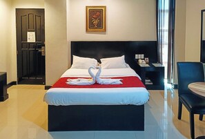 A hotel room with a bed, a nightstand, a chair, and a door. - Check Inn Hotel Dumaguete City By Reddoorz (Dumaguete)