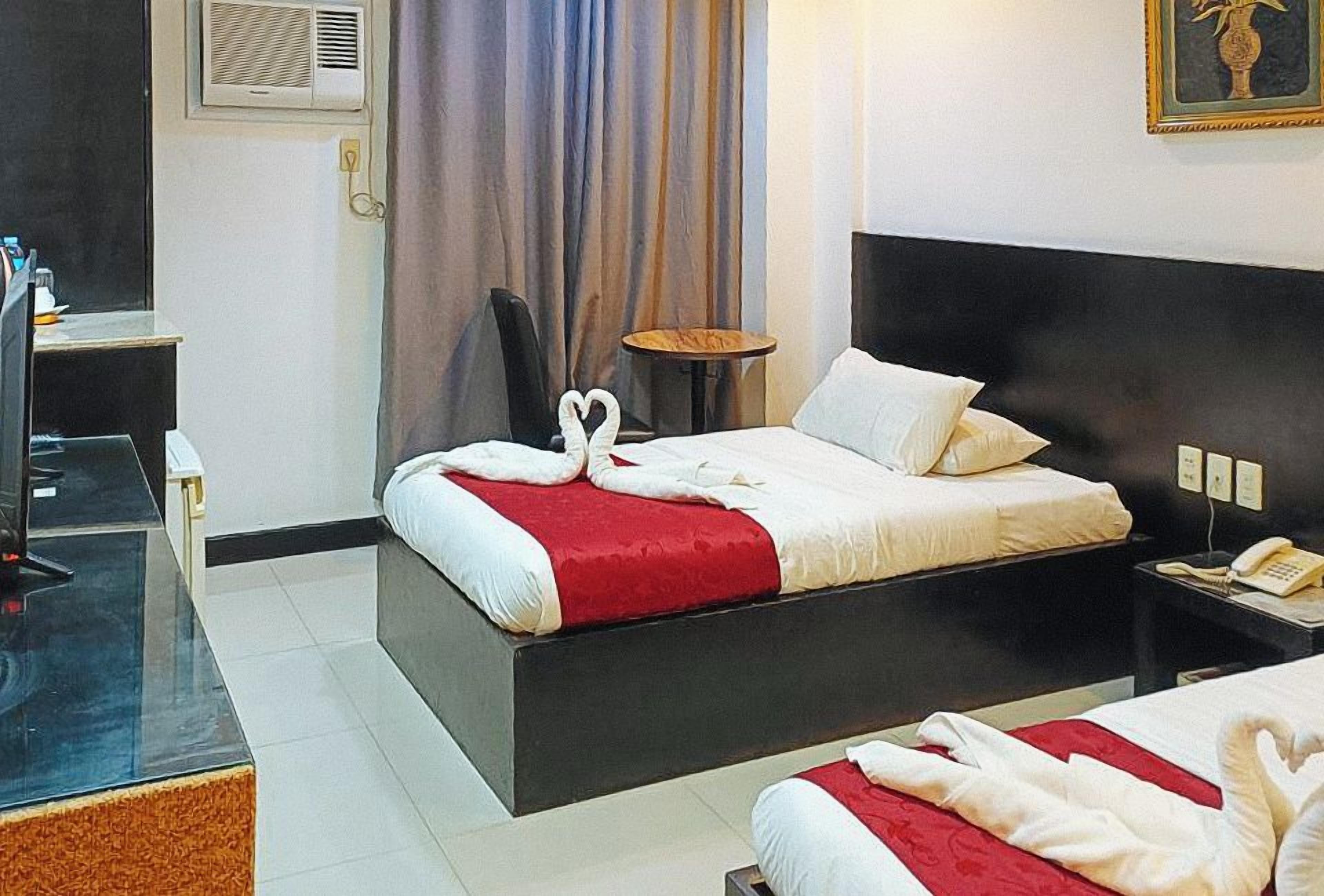 A hotel room with a bed, bedside table, and a small round table.
