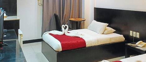 A hotel room with a bed, bedside table, and a small round table.
