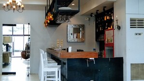 A modern kitchen with a bar area, white chairs, and a chandelier.