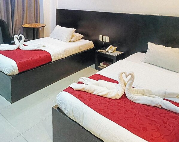 A hotel room with two beds, each with a red and white bedspread and white pillows. There are two bedside tables with lamps and a telephone. - Check Inn Hotel Dumaguete City By Reddoorz (Dumaguete)