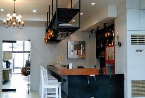A modern kitchen with a bar area, white chairs, and a chandelier. - Check Inn Hotel Dumaguete City By Reddoorz (Dumaguete)
