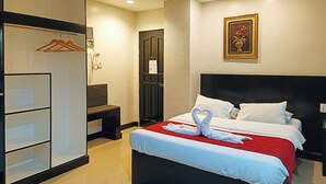 A hotel room with a bed, a wardrobe, a desk, and a wall-mounted picture.