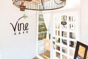 A cafe interior with a sign reading "Vine Cafe" and a door with a sign that says "OPEN". - Check Inn Hotel Dumaguete City By Reddoorz (Dumaguete)