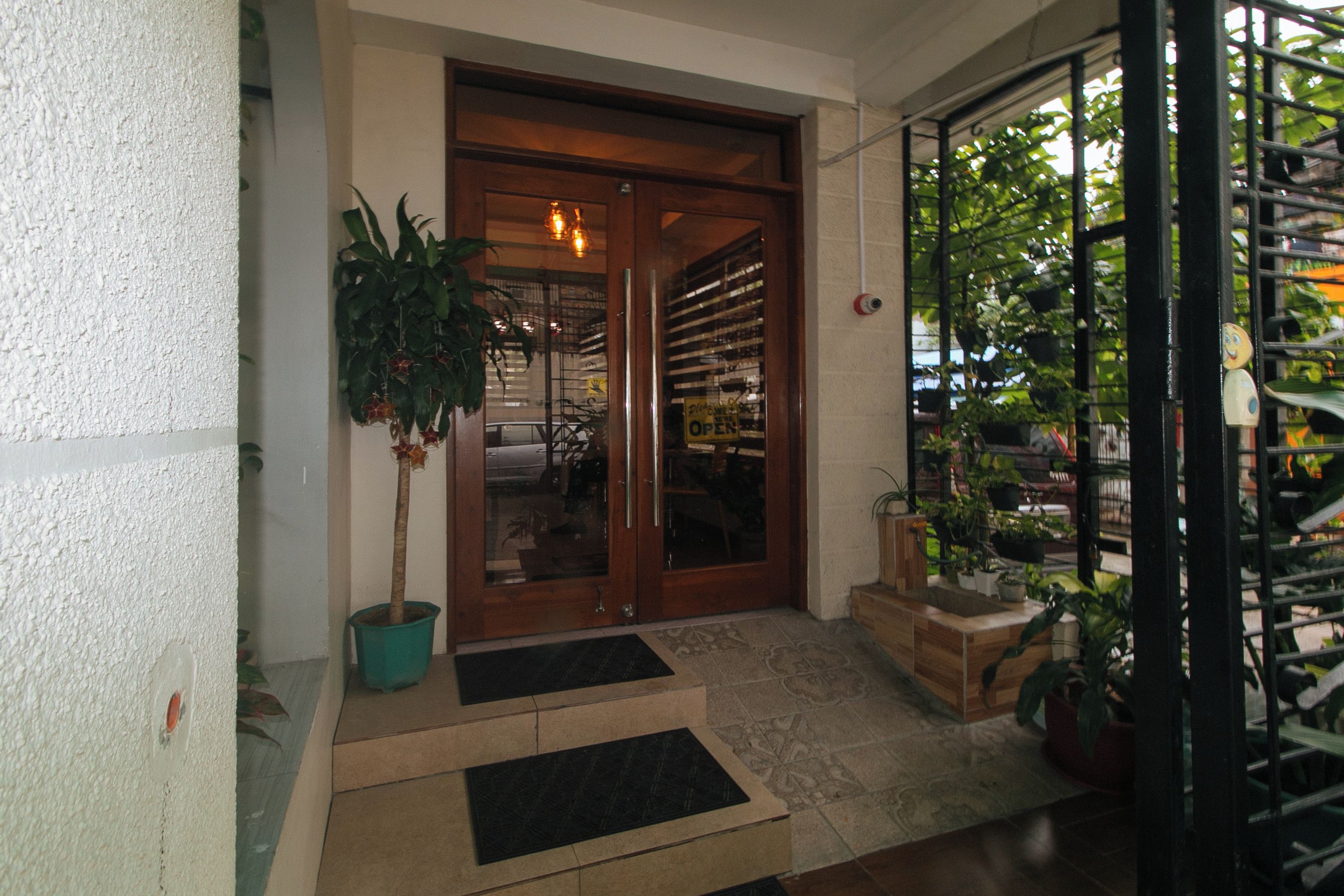A wooden door with glass panels, a potted plant, and a tiled entrance area.