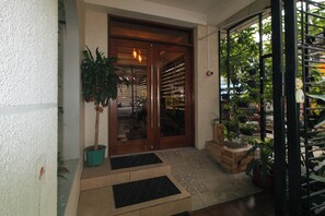 A wooden door with glass panels, a potted plant, and a tiled entrance area.