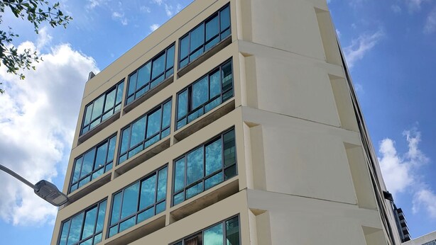 Un edificio de varios pisos con ventanas amplias y unidades de aire acondicionado en la planta baja.