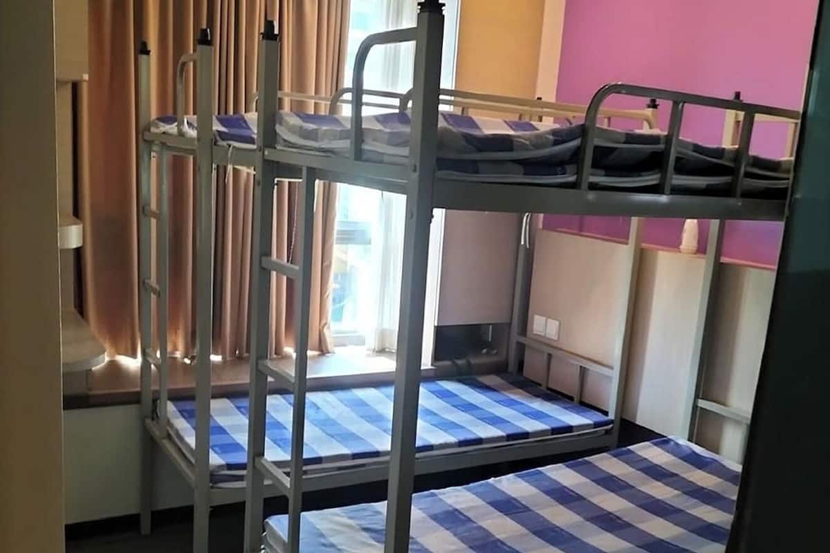 Une chambre avec un lit superposé, une fenêtre, des rideaux et un mur rose.