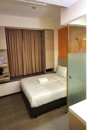 Une chambre d’hôtel avec un lit, une petite table sur laquelle se trouve une machine à café, un rideau et une porte vitrée donnant sur une salle de bain.