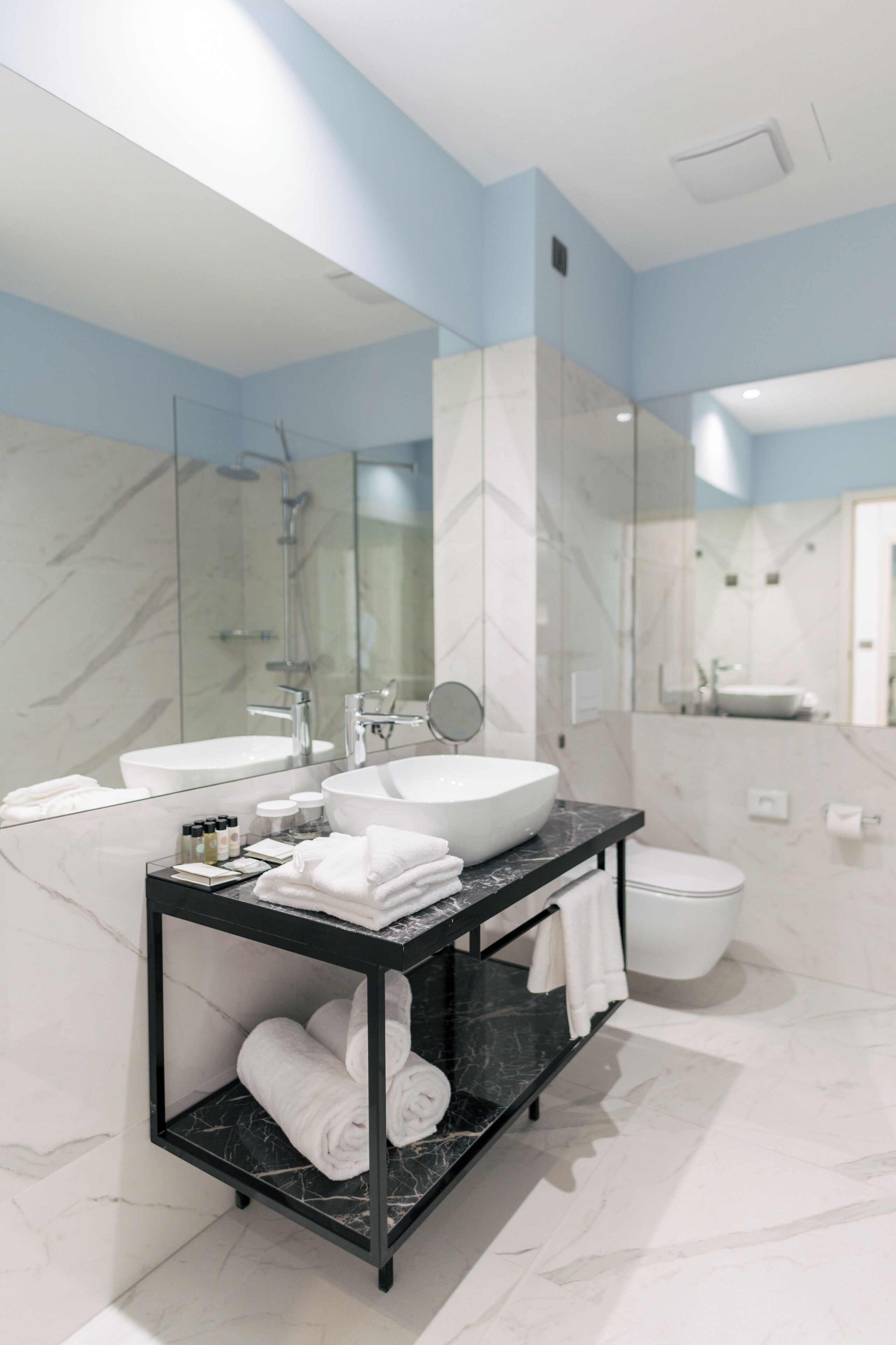 Un baño moderno con un espejo grande, dos lavamanos, un mueble de tocador negro y un inodoro.