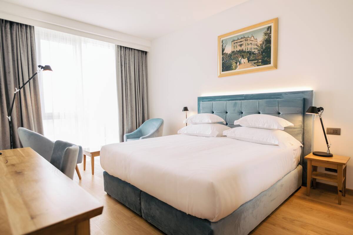 Hotellihuone, jossa on suuri sänky, työpöytä, tuoli ja pieni pöytä.