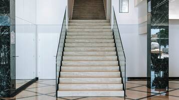 A modern interior with a staircase, marble flooring, and a circular light fixture.
