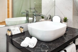 A modern bathroom with a large white sink, a black marble countertop, and a glass shower enclosure. - Miramare (Crikvenica)