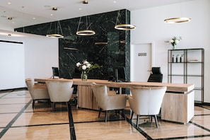 A modern reception area with a marble wall, a wooden reception desk, and a black shelving unit. - Miramare (Crikvenica)