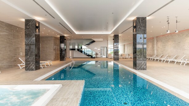 An indoor swimming pool with clear water, surrounded by lounge chairs and a modern interior design. - Miramare (Crikvenica)