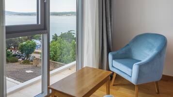 A room with a large window, a blue armchair, and a wooden table.