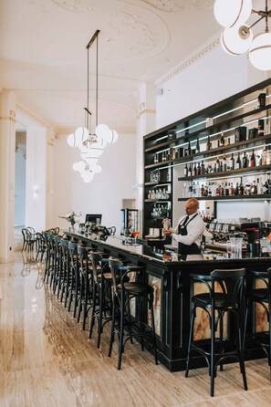 A bar area with a bartender, a long counter, and multiple stools. - Miramare (Crikvenica)