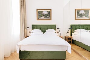 A neatly arranged bedroom with a green upholstered bed, white bedding, two bedside tables with lamps, and framed pictures on the wall. - Miramare (Crikvenica)