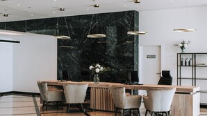 A modern reception area with a marble wall, a wooden reception desk, and a seating area with chairs. - Miramare (Crikvenica)