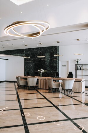 A modern reception area with a marble wall, a wooden reception desk, and a seating area with chairs. - Miramare (Crikvenica)