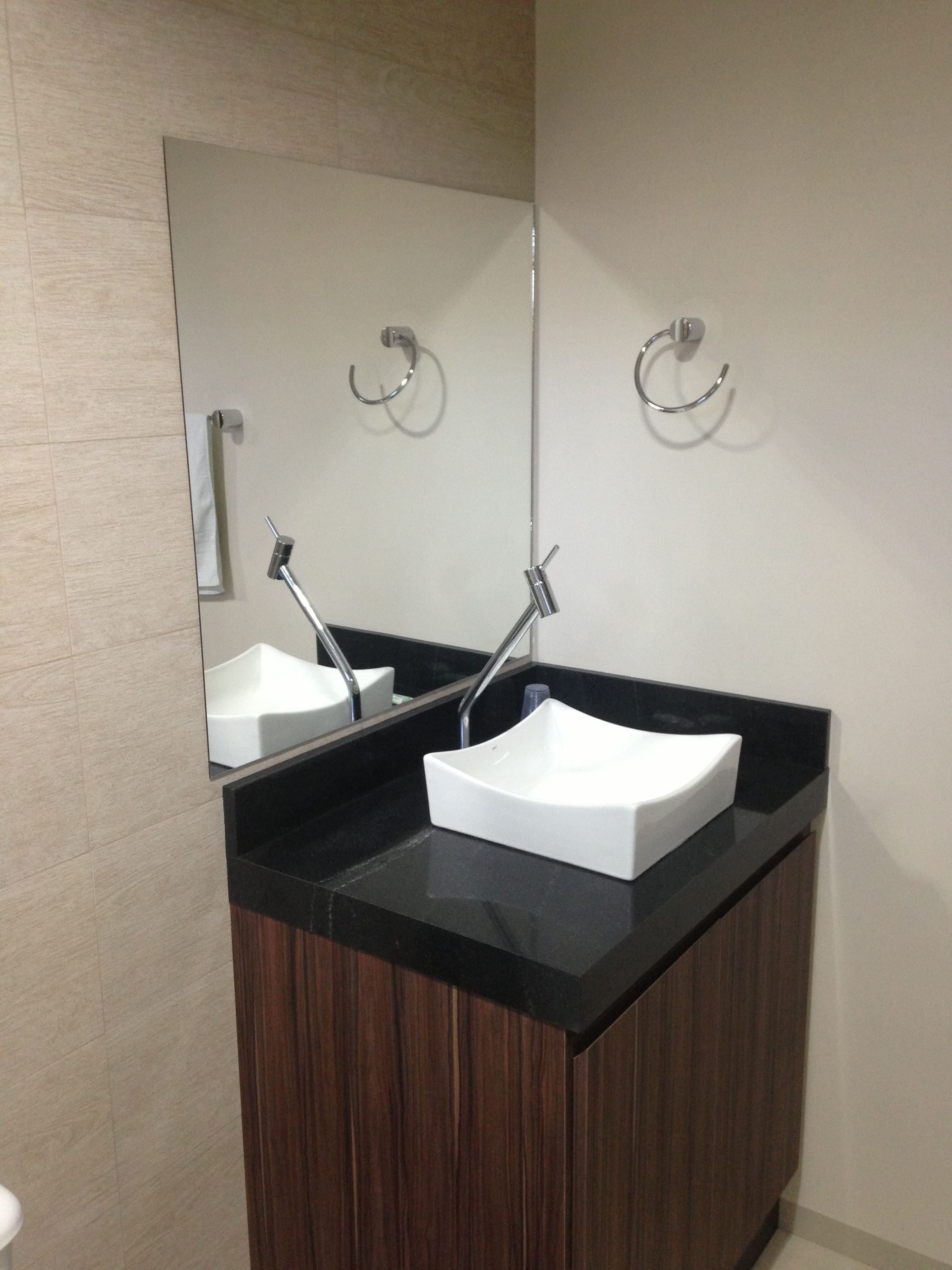 A bathroom with two sinks, a mirror, and towel hooks.