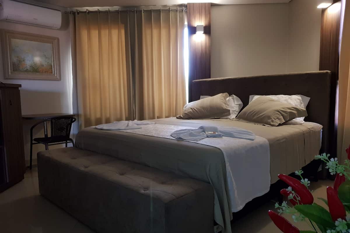 A neatly arranged bedroom with a bed, a bedside table, a chair, and a small table.