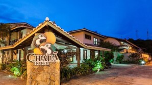 The exterior of Chaua Hotel with a stone sign featuring a sloth design, surrounded by lush greenery and a paved driveway. - Chaua Porto Hotel (Porto Seguro)