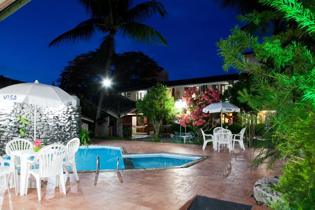 A pool area with white chairs and tables, a stone wall, and a Visa-branded umbrella.