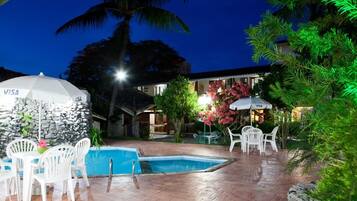 A pool area with white chairs and tables, a stone wall, and a Visa-branded umbrella.