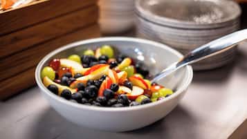 A bowl of mixed fruit salad with a spoon.