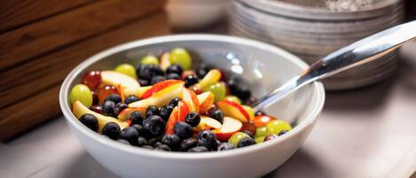 Uma saladeira com salada de frutas variadas e uma colher.