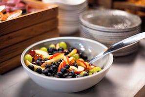 A bowl of mixed fruit salad with a spoon. - Wilde Aparthotels London Aldgate Tower Bridge (London)