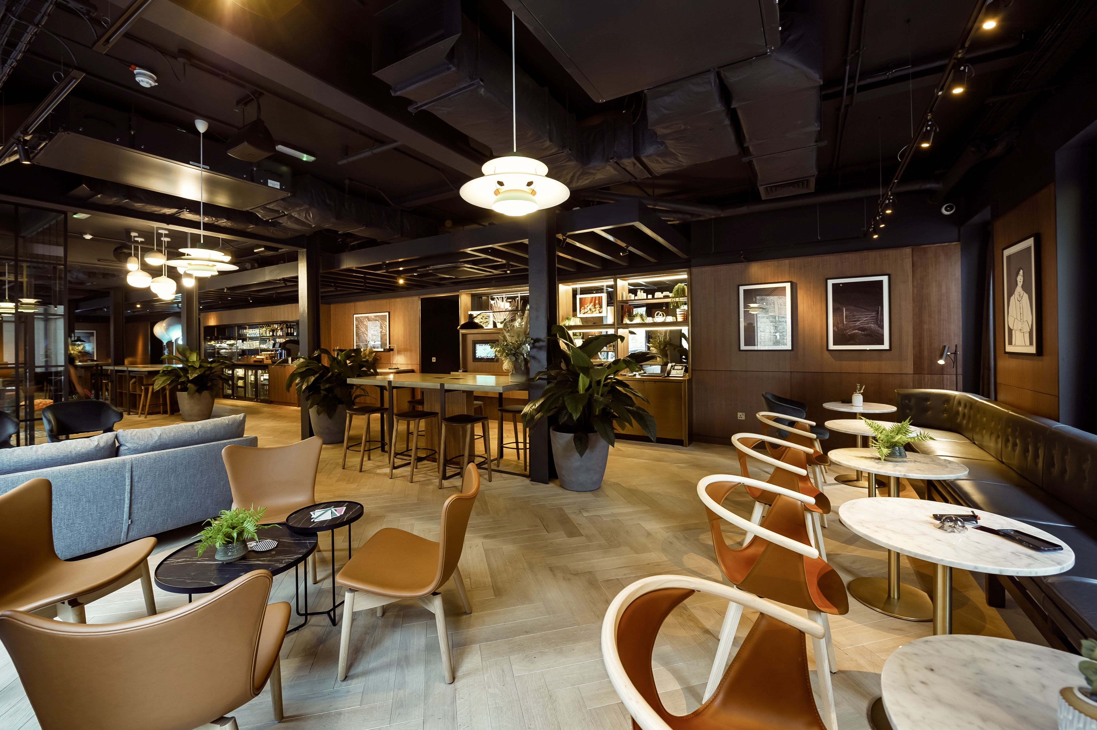A modern cafe with round tables, cushioned seating, and pendant lighting.