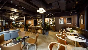 A modern cafe with round tables, cushioned seating, and pendant lighting.