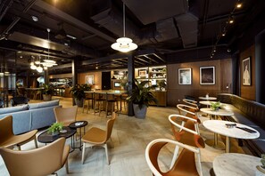 A modern cafe with round tables, cushioned seating, and pendant lighting. - Wilde Aparthotels London Aldgate Tower Bridge (London)