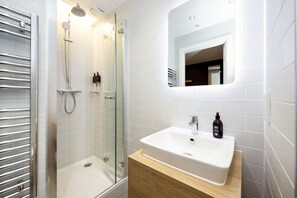 Une salle de bain moderne avec une douche à parois de verre, un lavabo blanc et un meuble-lavabo en bois.