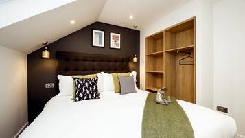 A modern bedroom with a large bed, a wooden wardrobe, and two wall-mounted lights.
