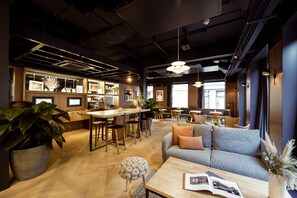 A modern interior with a bar area, seating, and a large plant. - Wilde Aparthotels London Aldgate Tower Bridge (London)