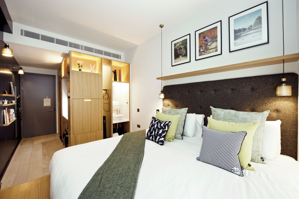 Une chambre d’hôtel moderne dotée d’un grand lit, d’une armoire et d’un espace bureau.