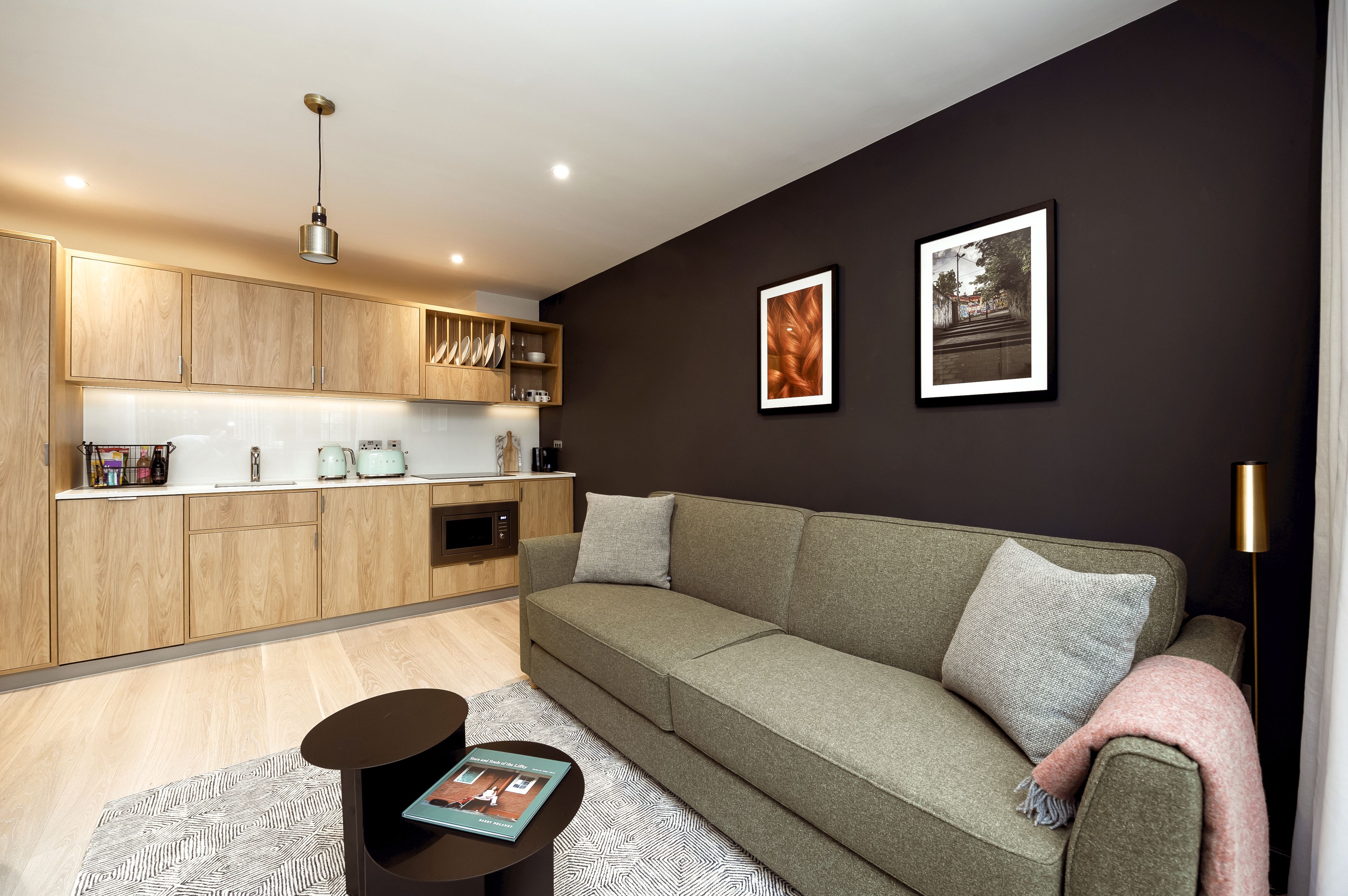 Una sala de estar moderna con un sofá verde, armarios de madera y una lámpara de pie negra.