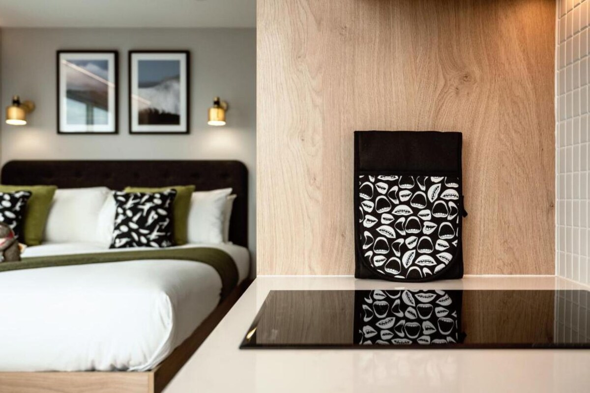 Une chambre d’hôtel avec un lit, une table de chevet et une œuvre d’art accrochée au mur.