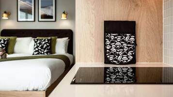 Quarto de hotel com uma cama, mesa de cabeceira e uma obra de arte pendurada na parede.