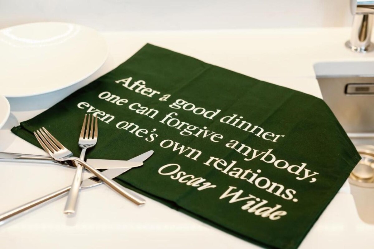 Un set de table vert orné d’une citation d’Oscar Wilde, posé sur une table avec des couverts.