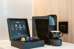 A coffee machine and a coffee pod holder with various pods. - Wilde Aparthotels London Aldgate Tower Bridge (London)
