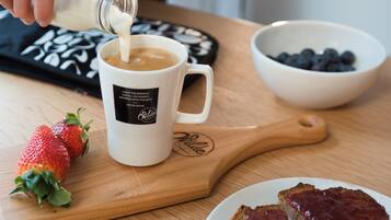 A coffee mug on a wooden board, a bowl of blueberries, and a plate with toast.