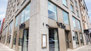 En moderne bygning med skiltet 'Wilde' på facaden, store vinduer og et velkomstskilt ved indgangen.